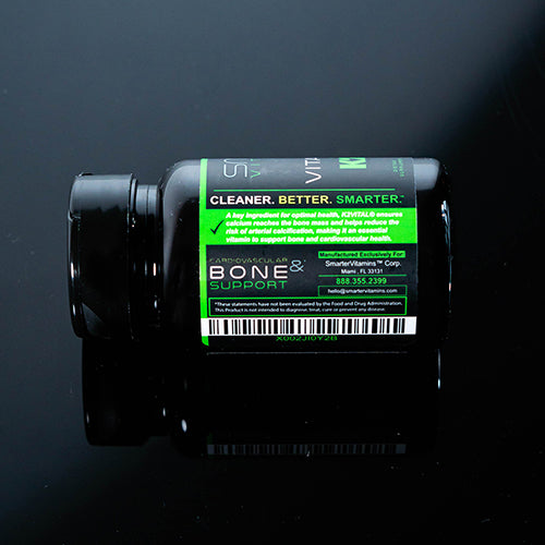 Bottle of Smarter Vitamin K2 laying sideways on a black table