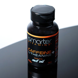 a bottle of Smarter Caffeine + L-Theanine made with MCT Oil on a black reflective table.