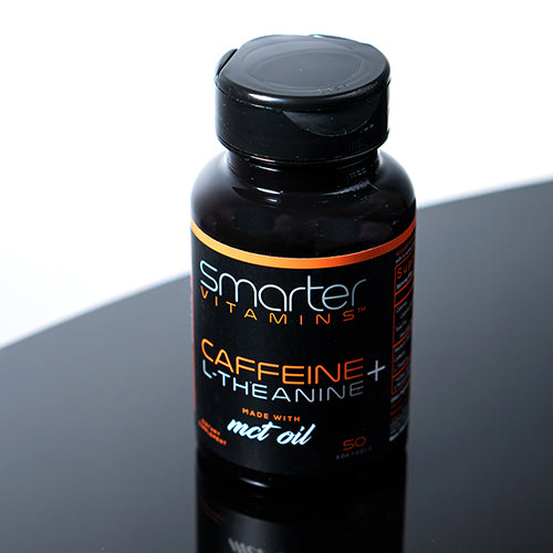 a bottle of Smarter Caffeine + L-Theanine made with MCT Oil on a black reflective table.